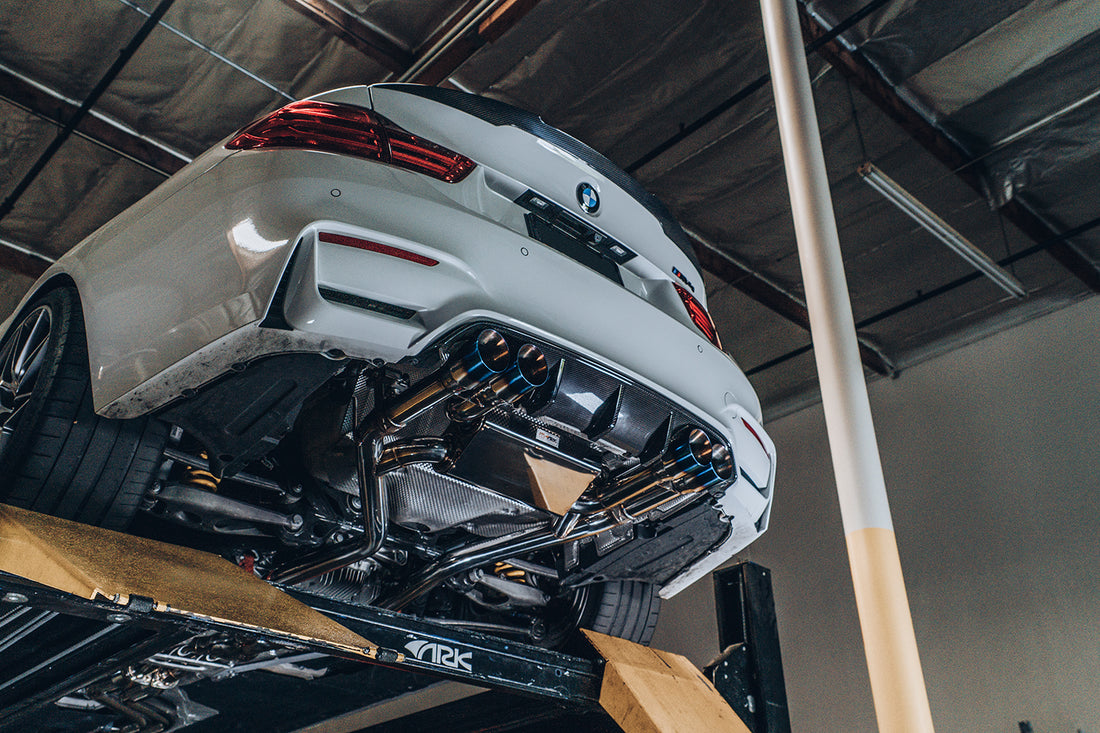 A view from under a BMW M4 of the ARK DT-S Exhaust System with Burnt Tips